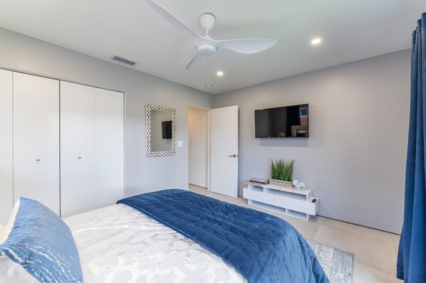 A modern bedroom with a bed, a ceiling fan, a TV, and a wardrobe. - Modern Oasis, Heated Pool, Short Drive to Beach (Fort Lauderdale)