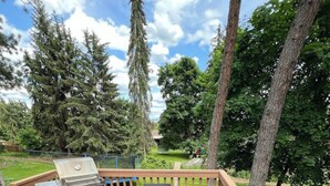Une terrasse en bois avec un barbecue, deux chaises et une table.