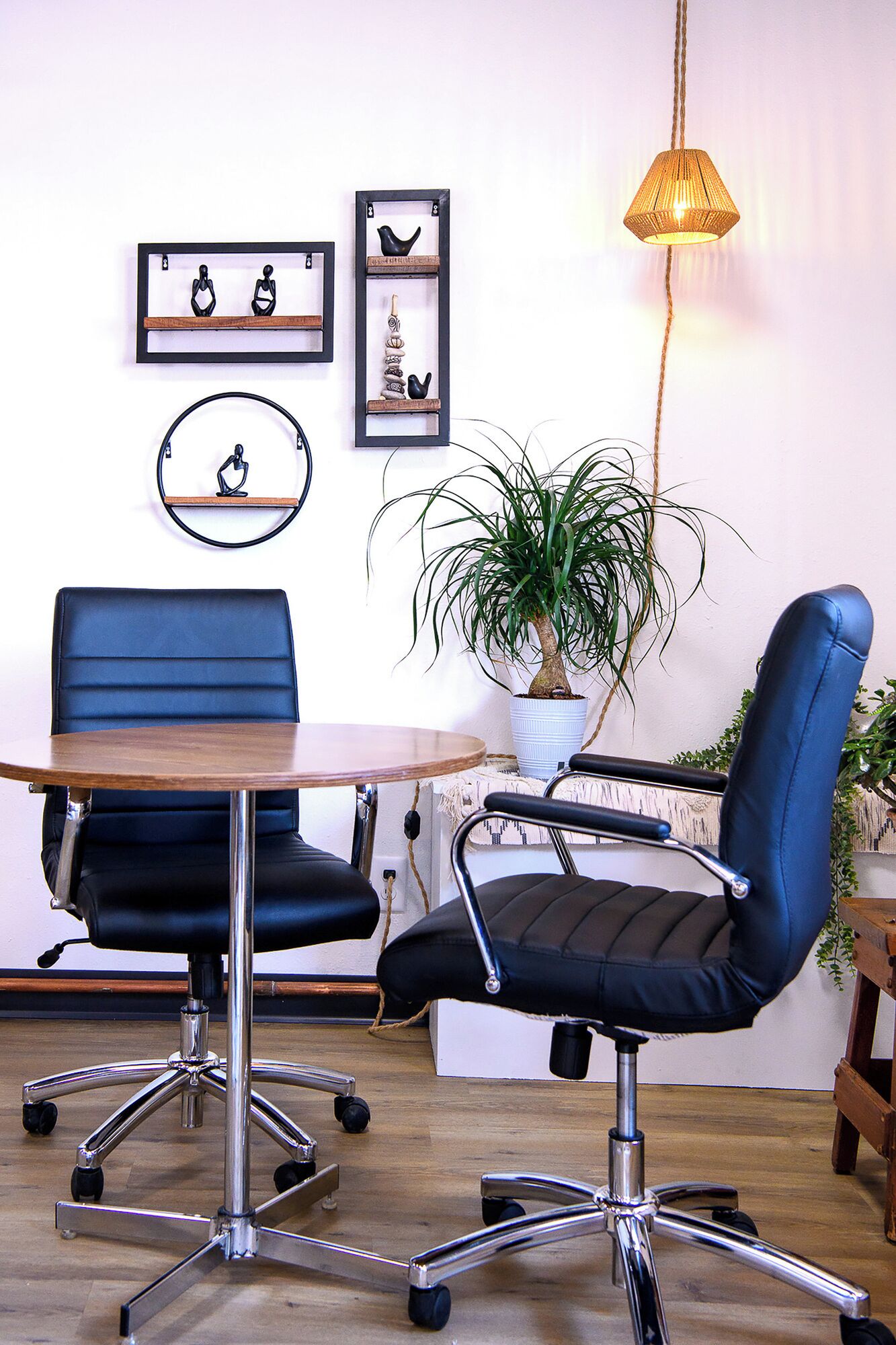 A modern office space with two blue office chairs, a wooden table, and a hanging lamp.