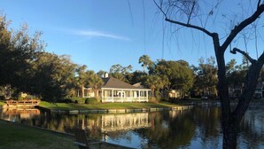 A house with a large lawn and a pond in front.