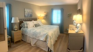 A bedroom with a bed, bedside tables, lamps, and artwork on the walls.