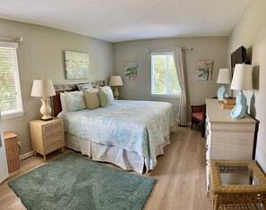 A bedroom with a bed, bedside tables, a dresser, and a window with curtains.