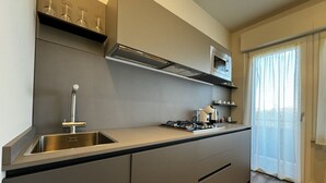 A modern kitchen with a stainless steel sink, a microwave, and a gas stove. - Skyline-Bluemoon ( studio apartment with a view) (Siena)