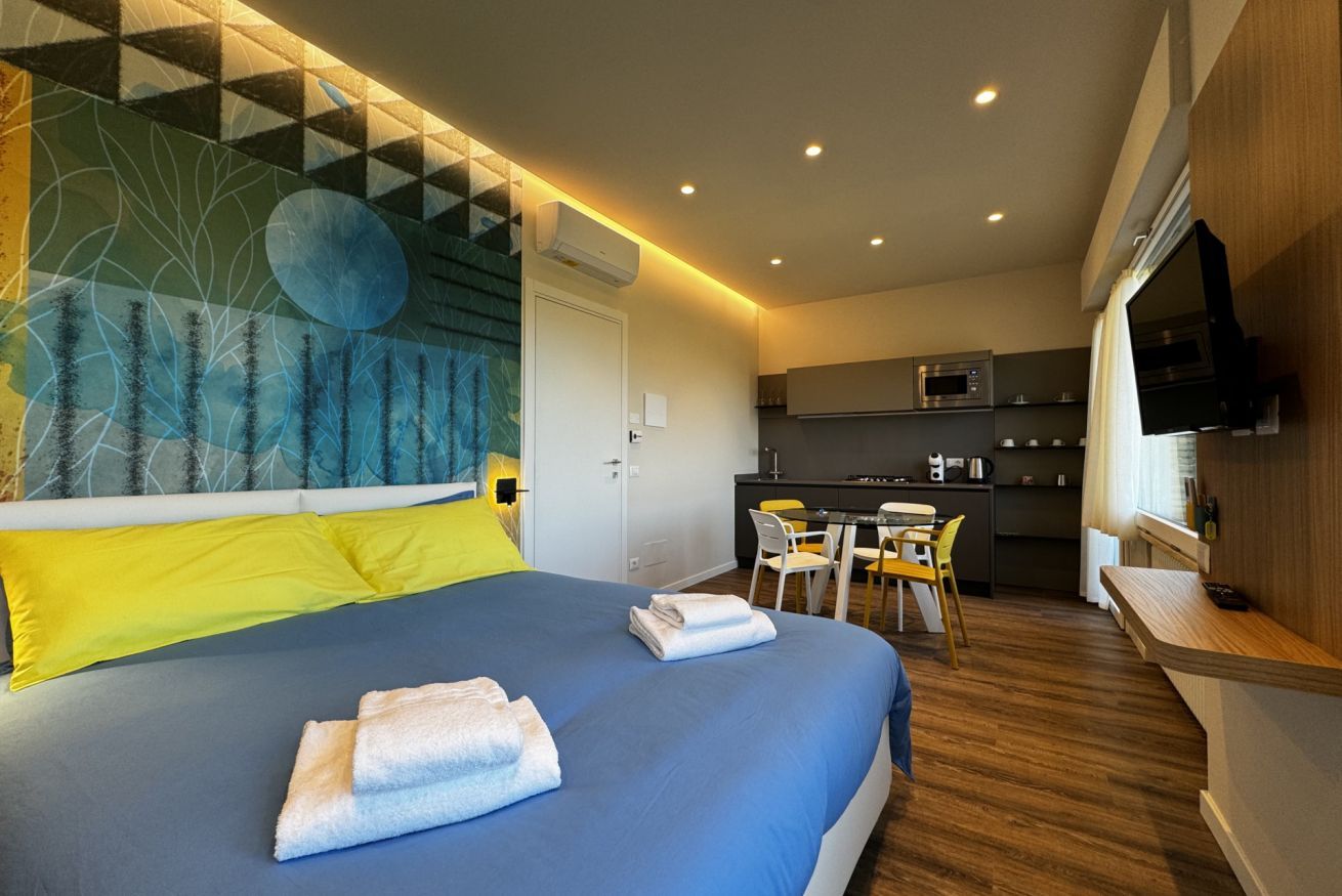 Een moderne hotelkamer met een groot bed, een zithoek en een kitchenette.