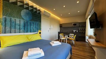 Een moderne hotelkamer met een groot bed, een zithoek en een kitchenette.