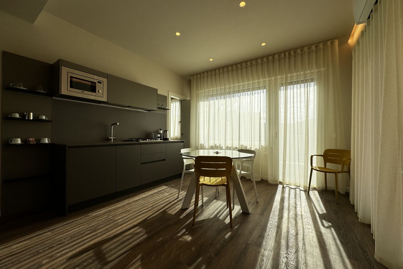 Una cucina moderna con forno a microonde, armadietti e zona pranzo con tavolo e sedie.