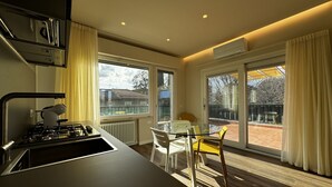 A modern kitchen with a gas stove, a sink, and a dining area with a table and chairs. - Skyline- Moncheri ( Studio apartment with a view) (Siena)