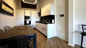 A modern kitchen with white cabinetry, a wooden dining table, and a built-in oven. - On the way to the sun ( Apartment with air conditioning) (Siena)