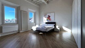 A modern bedroom with a large bed, a radiator, a window with a view, and a ceiling light fixture. - On the way to the sun ( Apartment with air conditioning) (Siena)
