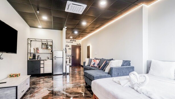 A modern hotel room with a marble floor, a sofa, a bed, a small kitchenette, and a TV. - Melwood Suites Unit 105 Studio (Pittsburgh)