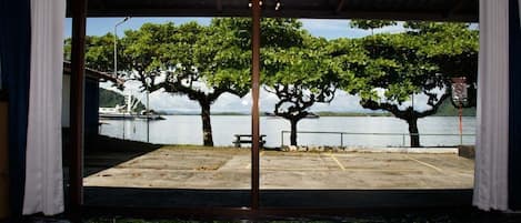 Ein Zimmer mit einem großen Glasfenster, das Blick auf einen See, Bäume und einen Steg bietet.