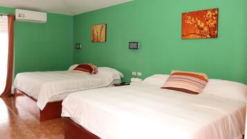 Una habitación con dos camas, paredes verdes y piso de madera.