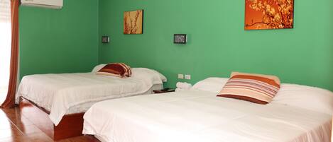 A room with two beds, green walls, and a wooden floor.