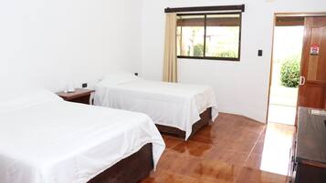 Habitación de hotel con dos camas individuales, un armario de madera, una ventana con cortina y suelo de baldosas.