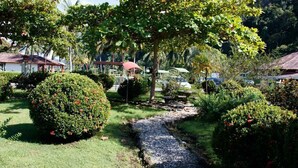 A well-maintained garden with a gravel path, neatly trimmed bushes, and a small bridge. - Hotel Samoa del Sur (Golfito)
