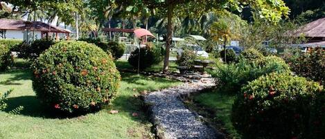 Un jardín bien cuidado con un sendero de grava, setos ordenados y un pequeño puente.