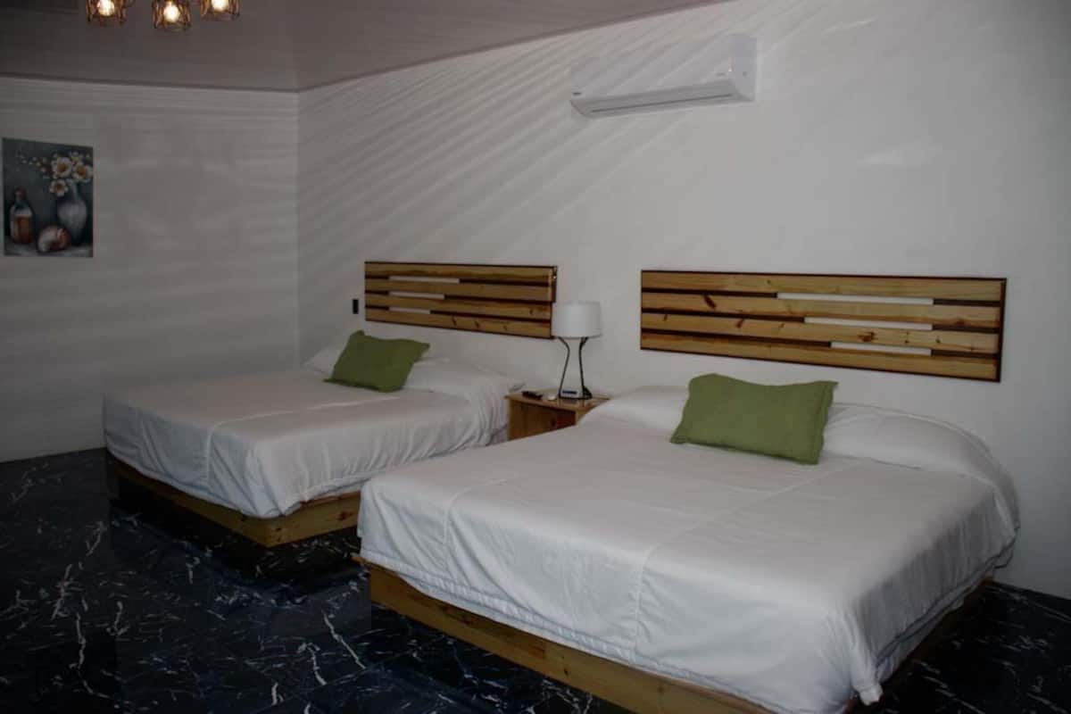 A hotel room with two beds, each with a wooden headboard and white bedding.
