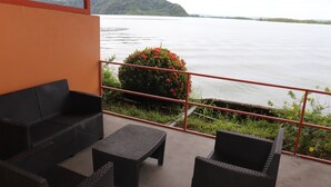 A balcony with wicker furniture, a view of a lake, and a red railing. - Hotel Samoa del Sur (Golfito)