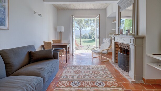 Uma sala de estar com sofá, lareira, área de jantar e vista para o exterior.