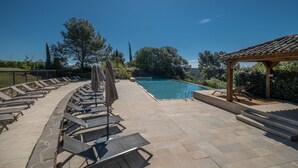 Uma área à beira da piscina com espreguiçadeiras e um pérgola.