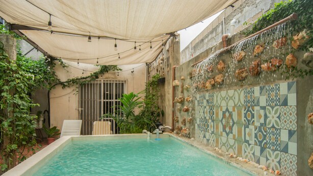A swimming pool with a tiled wall and a canopy overhead.