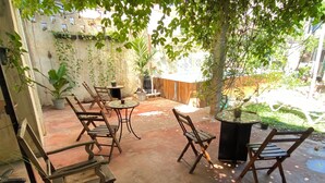 An outdoor patio with wooden furniture, potted plants, and a stone wall.