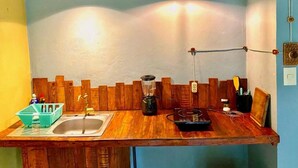 Una cocina con detalles de madera, un lavamanos, una licuadora y luces colgantes.