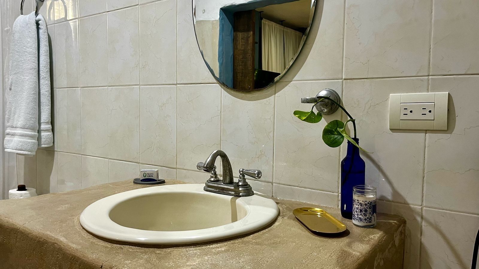Ein Badezimmer mit Waschbecken, Spiegel, Handtuchhalter und einer blauen Flasche auf der Ablagefläche.