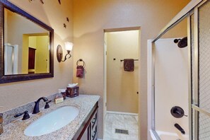 A bathroom with a sink, mirror, towel rack, and shower area.