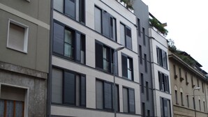 A multi-story building with a modern architectural style, featuring large windows with shutters, a flat roof, and a balcony on the upper floor. - Cola Montano Apartment (Milano)