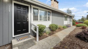A residential house with a black front door, white window frames, and a small porch with a white railing. - Charming 2-bedroom apartment with WiFi, AC in Olympia (Olympia)
