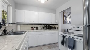 A modern kitchen with white cabinets, a stainless steel refrigerator, and a built-in oven. - Charming 2-bedroom apartment with WiFi, AC in Olympia (Olympia)