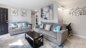 A modern living room with two grey sofas, a black coffee table, and abstract wall art. - Charming 2-bedroom apartment with WiFi, AC in Olympia (Olympia)