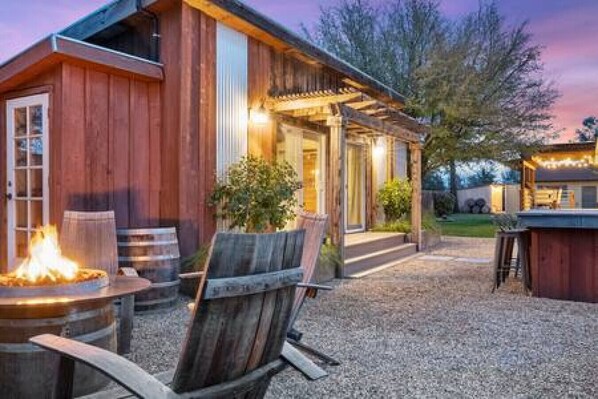 A rustic wooden building with a covered patio area, outdoor seating, and a fire feature.