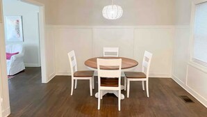 Un comedor con una mesa redonda de madera y cuatro sillas blancas.