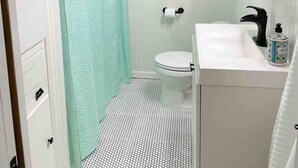 Un baño con inodoro, lavamanos y cortina de ducha.