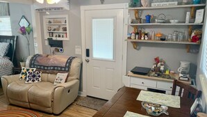 A cozy living room with a leather sofa, a dining table with placemats, and a bookshelf filled with various items. - The Unique cozy studio (Winter Haven)