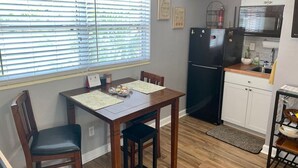 A compact kitchen with a dining table, chairs, a refrigerator, and a microwave. - The Unique cozy studio (Winter Haven)