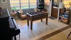 Ein Wohnzimmer mit Tischfußball, Klavier und Bücherregal.