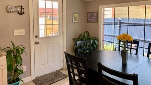 A dining area with a table and chairs, a potted plant, and a door with a window.