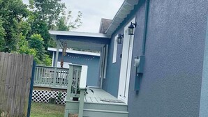 Una casa con fachada azul, una terraza de madera y una valla blanca.