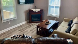 Una sala de estar con chimenea, televisor montado en la pared y un sofá.