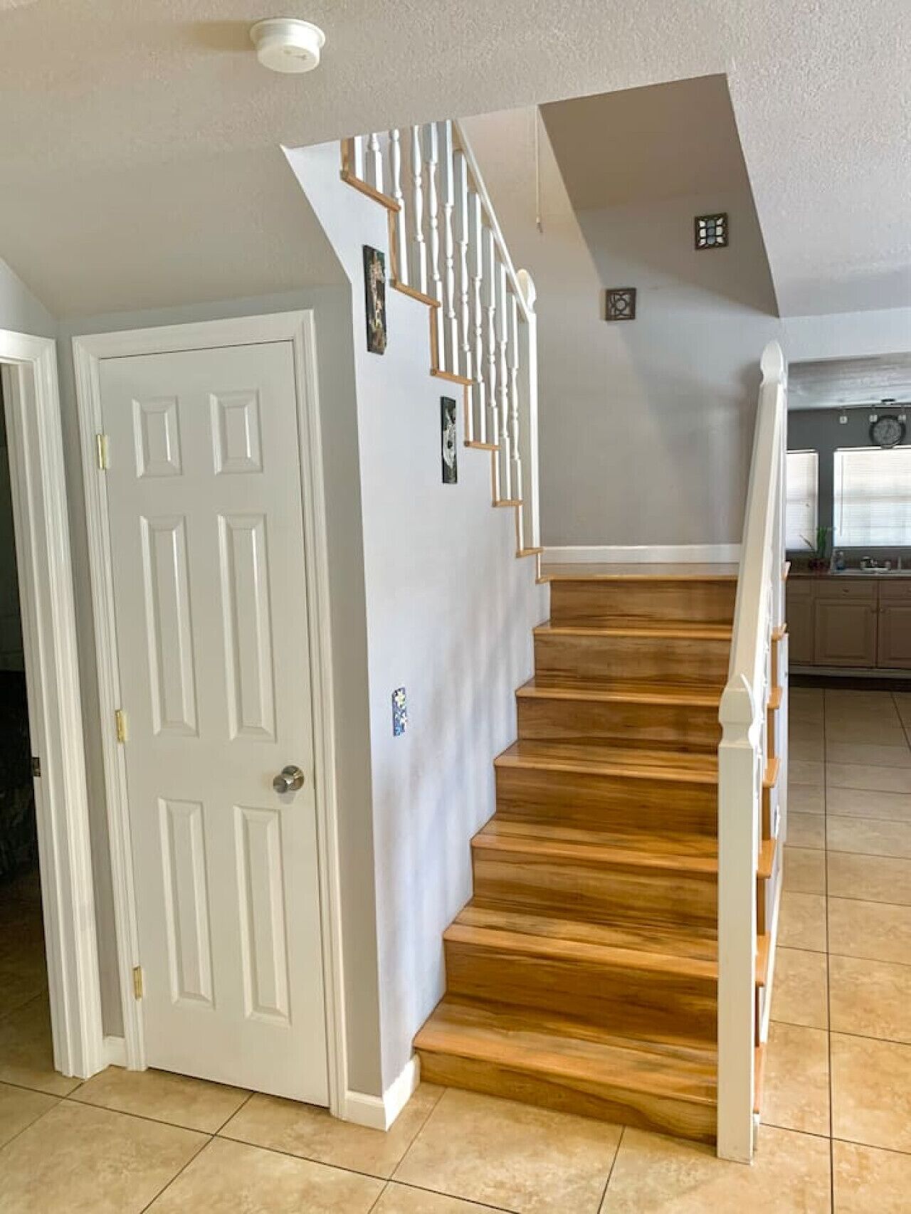 A staircase with wooden steps and white railings, leading to a landing with a white door and a small picture frame.