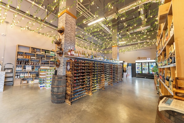 A wine cellar with wooden racks of wine bottles, a stone pillar, and hanging lights.