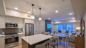 Una cocina moderna con una isla central, electrodomésticos de acero inoxidable e iluminación colgante.