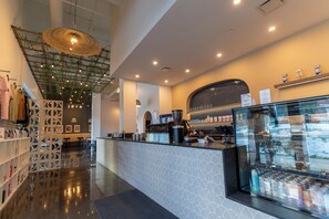 A modern interior with a central counter, a glass display case, and a ceiling with hanging lights and greenery.