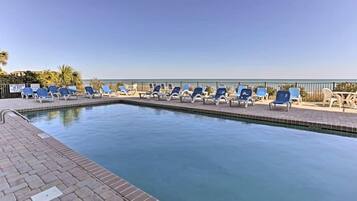 A swimming pool with lounge chairs and a view of the ocean.