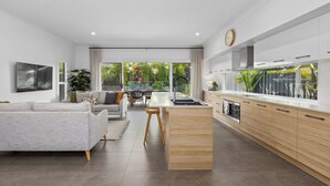 Une cuisine moderne dotée d’un îlot central, de meubles en bois et d’une grande fenêtre donnant sur un jardin.