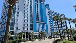 A high-rise hotel with multiple floors, a prominent blue and white facade, and a central entrance with a sign.