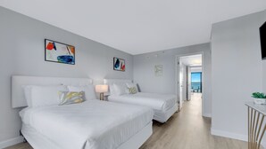 A modern hotel room with two beds, a small desk, and artwork on the walls.